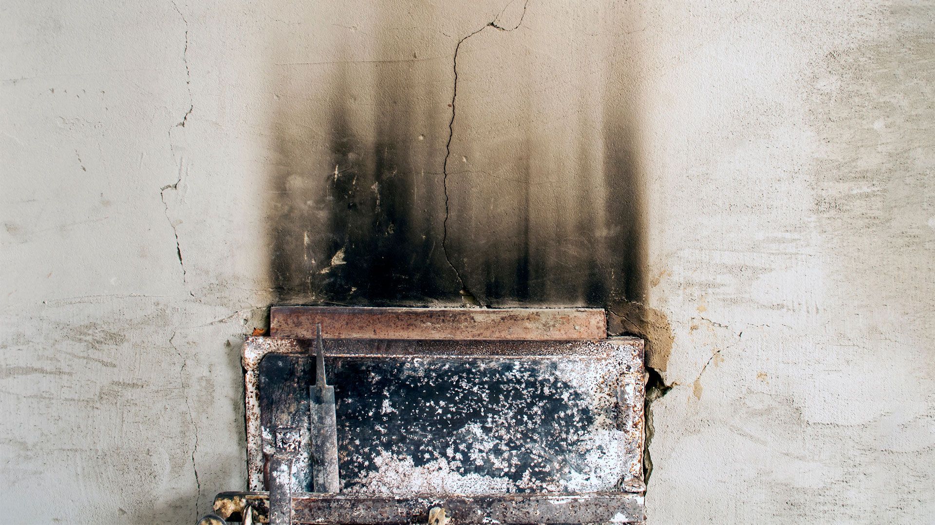A rusty metal box is sitting on a white wall.