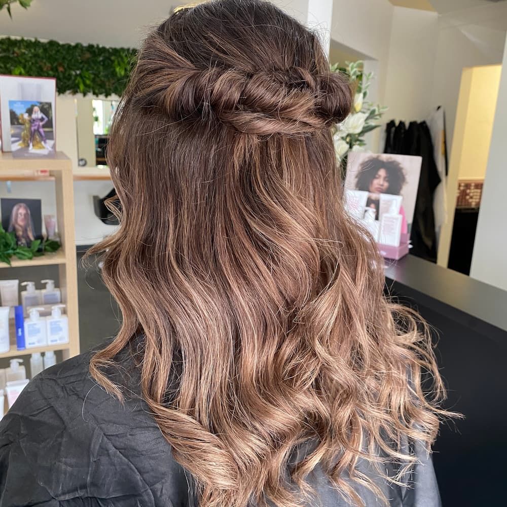 A Woman With Long Brown Hair Is Wearing A Braided Half Up Half Down Hairstyle — Haelo Hair In Bomaderry, NSW