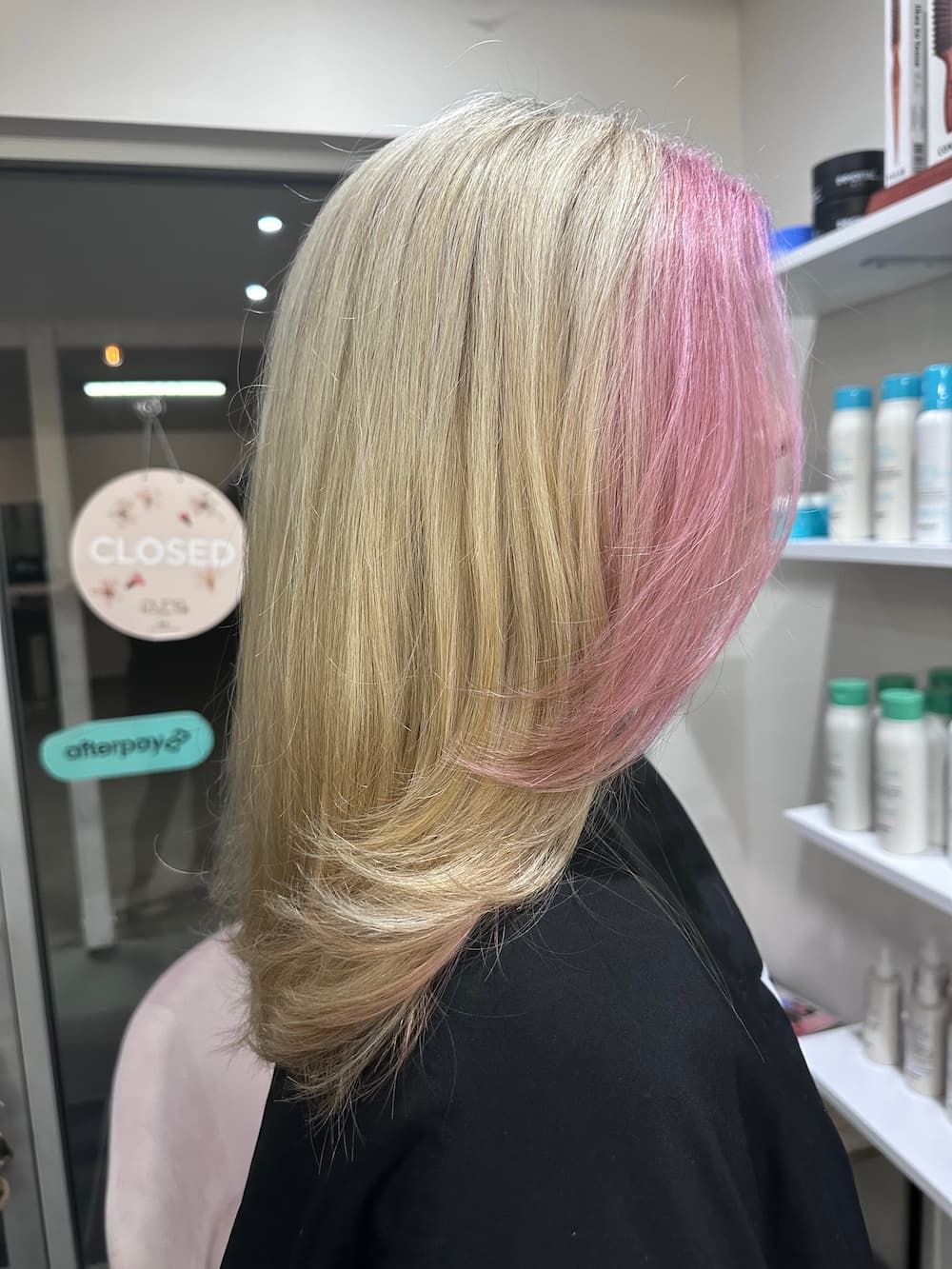 A Woman With Blonde And Pink Hair Is Standing In A Salon — Haelo Hair In Bomaderry, NSW