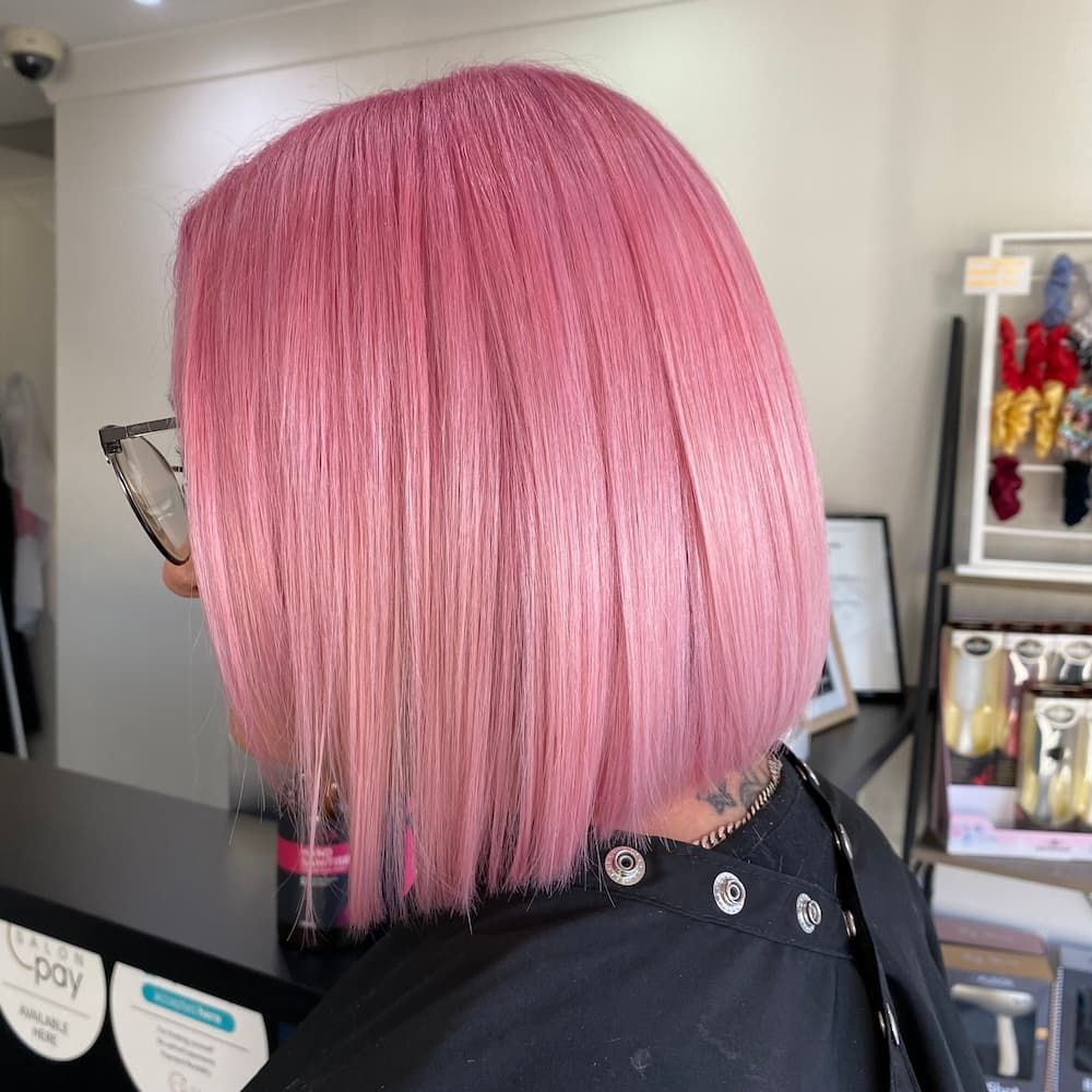 A Woman With Pink Hair Is Wearing Glasses And A Black Shirt In A Salon — Haelo Hair In Bomaderry, NSW