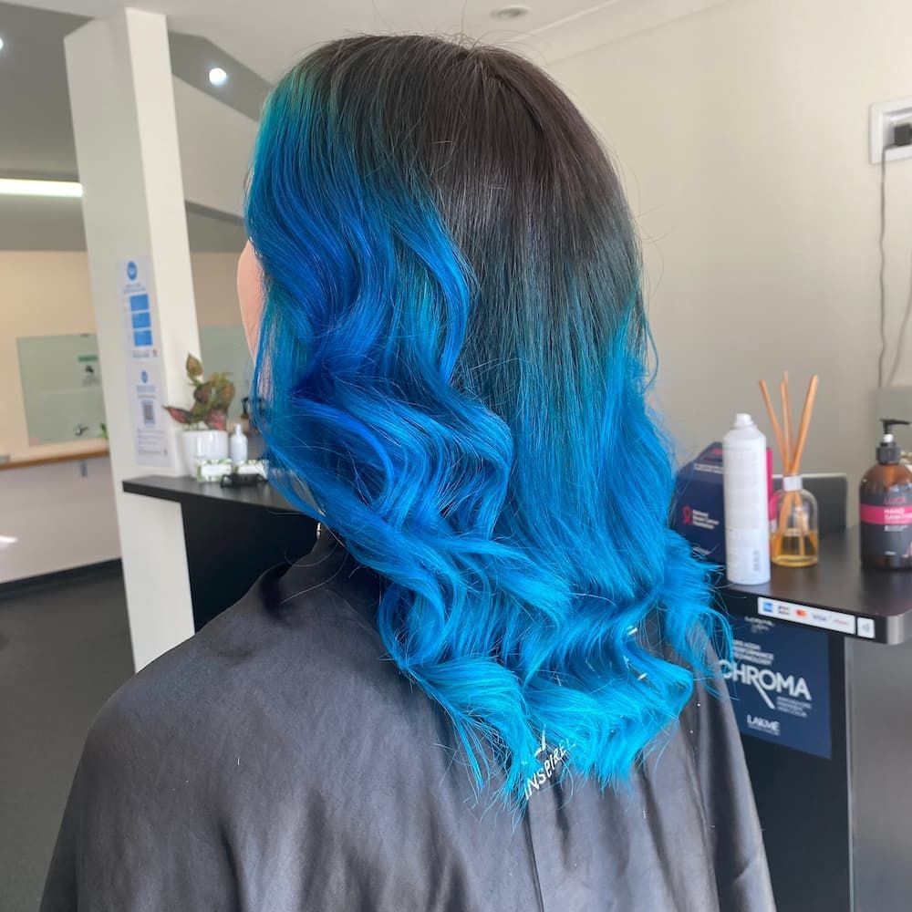 A Woman With Blue Hair Is Sitting In A Salon — Haelo Hair In Bomaderry, NSW