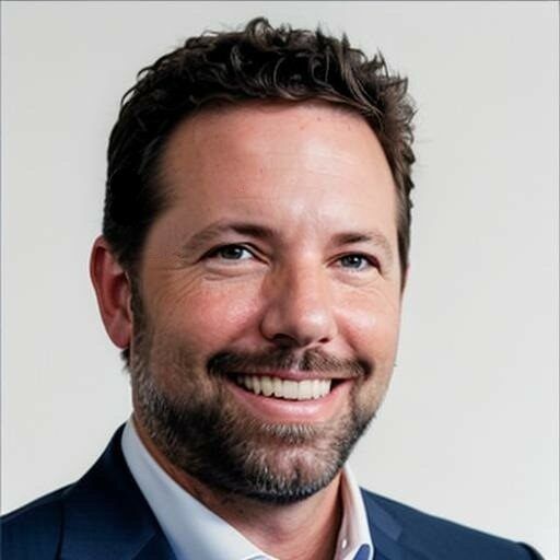 Smiling man with short dark hair and beard in a blue blazer.