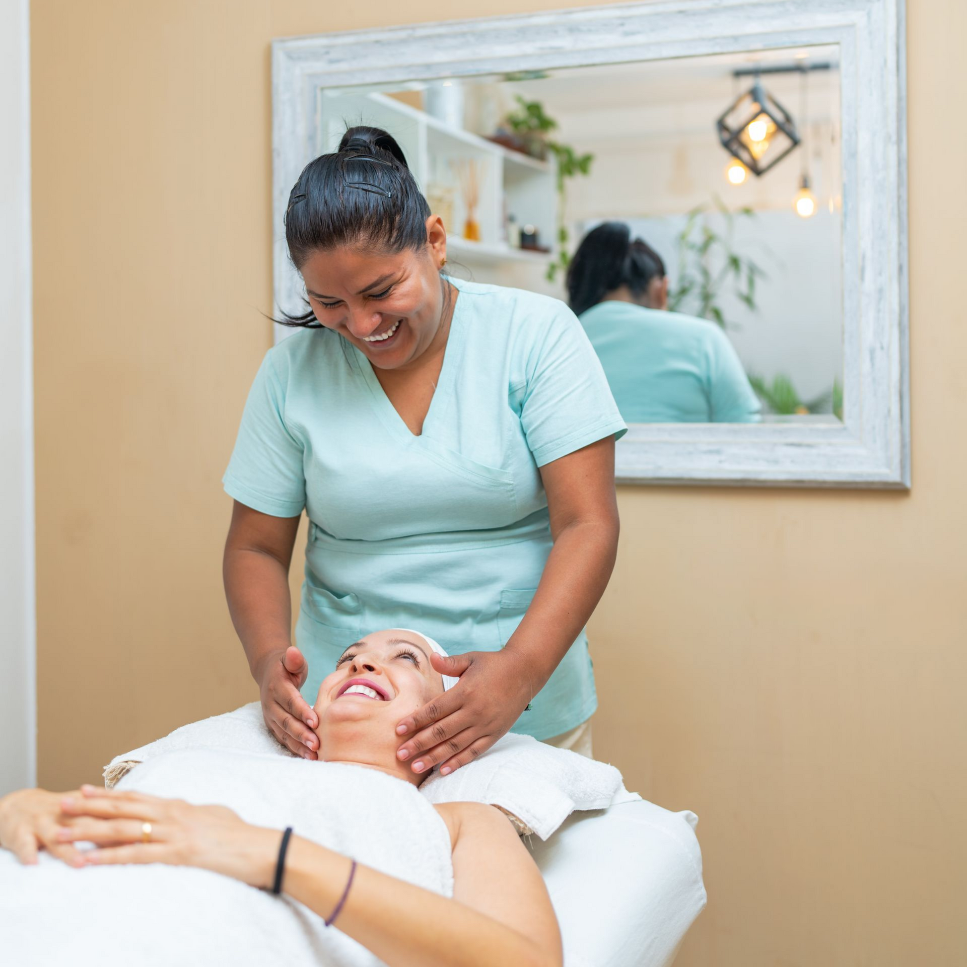 Woman receiving facial, esthetician smiling, spa setting.