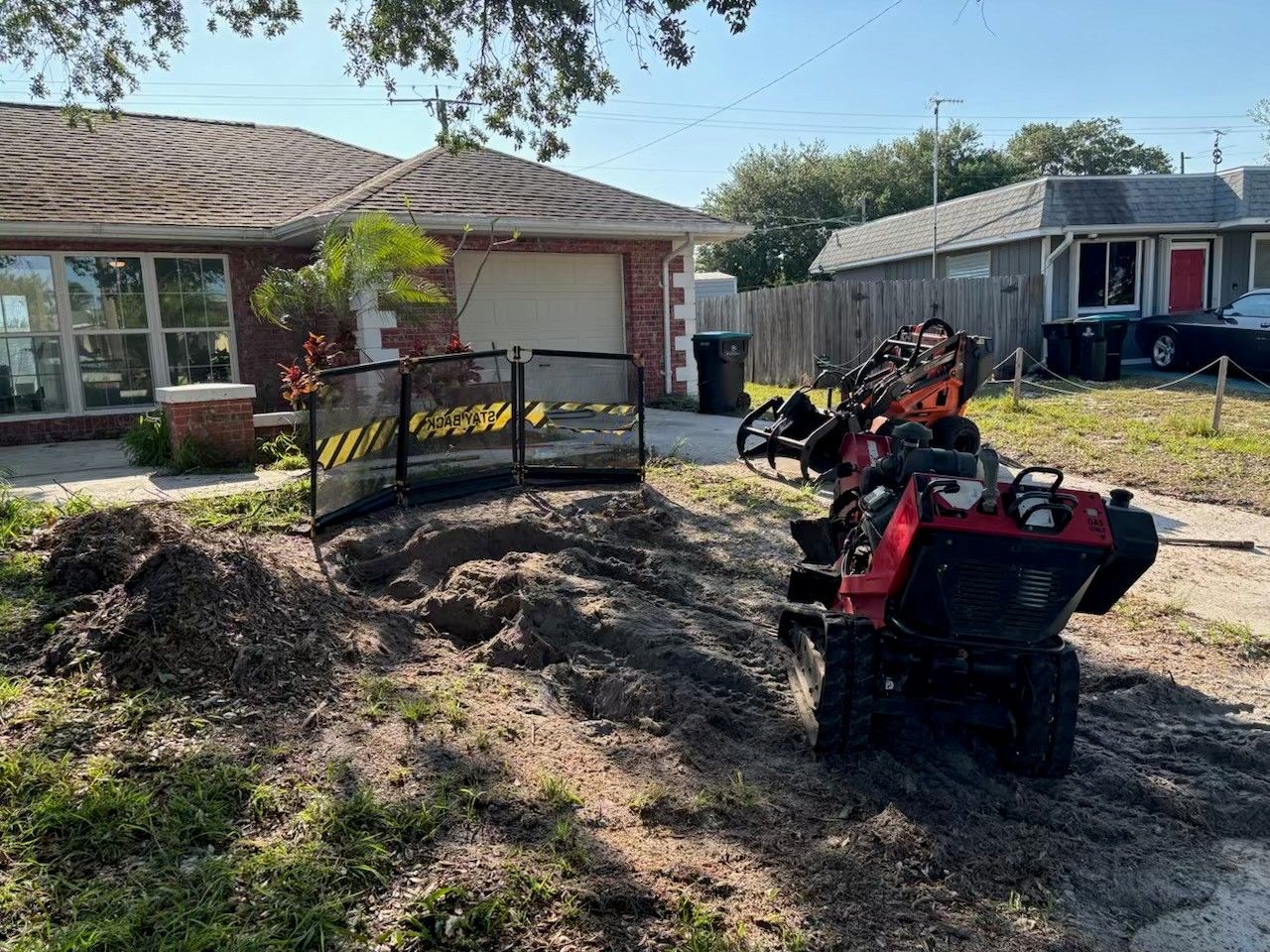 A stump grinder is sitting in the dirt in front of a house.