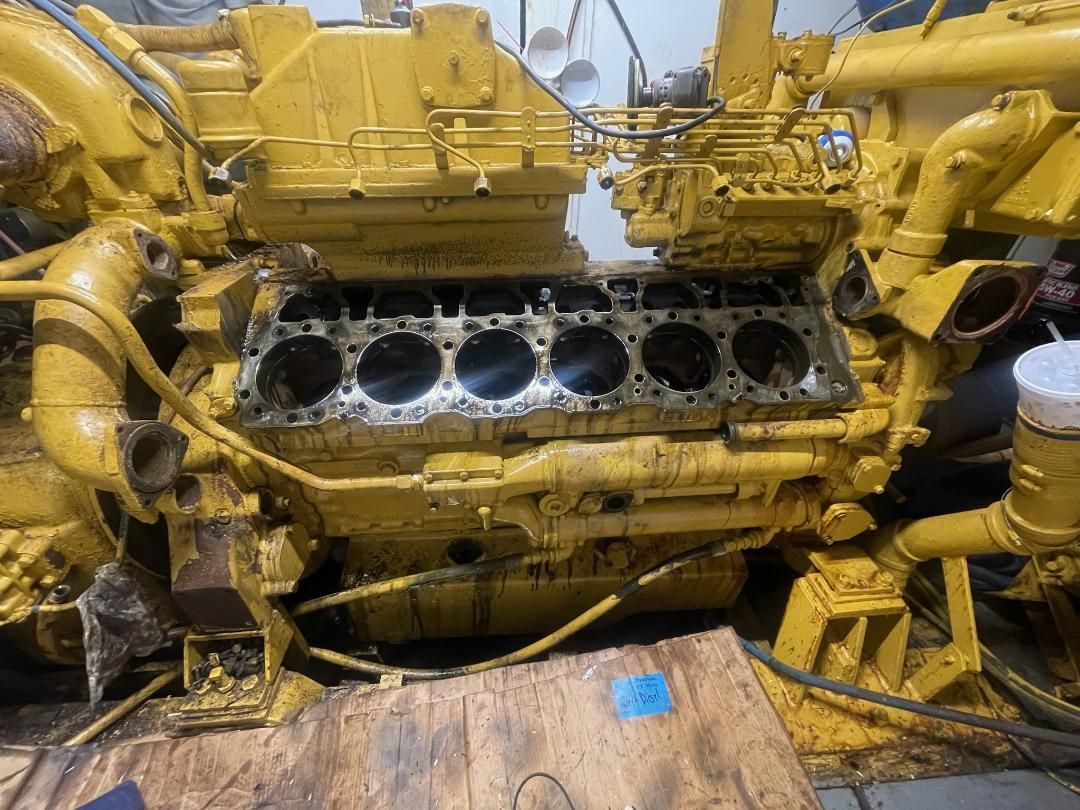 A large yellow marine engine is sitting on top of a wooden table.