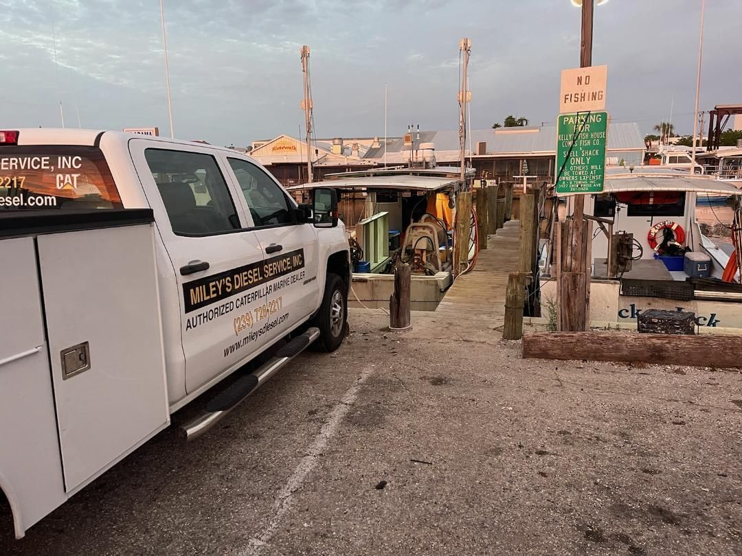 A Miley's Diesel white truck is parked in a parking lot next to a dock.