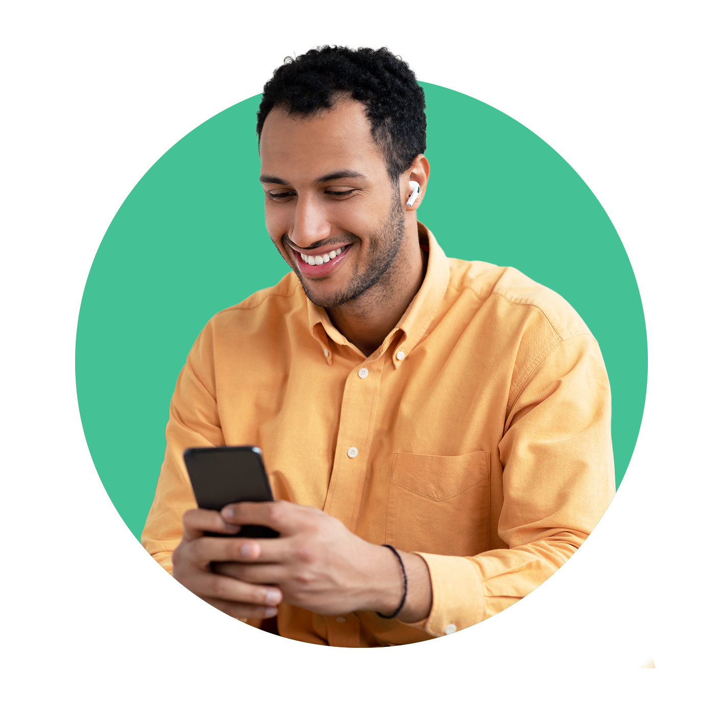 A man in a yellow shirt is smiling while looking at his cell phone.