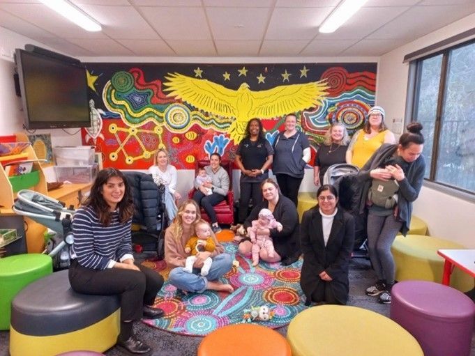 A group of people are posing for a picture in a room with a mural on the wall.