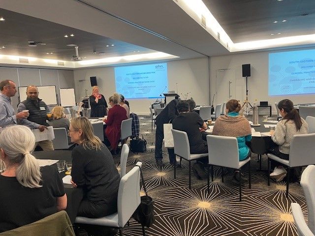A group of people are sitting at tables in a conference room.