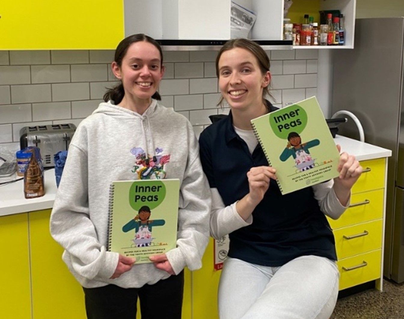 Two girls are holding a book called