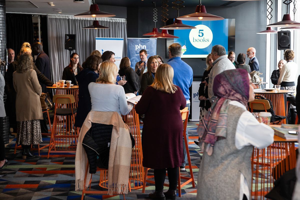 A group of people are standing and sitting around tables in a room