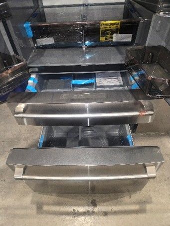 Stainless steel refrigerator drawers open, revealing shelves and contents.