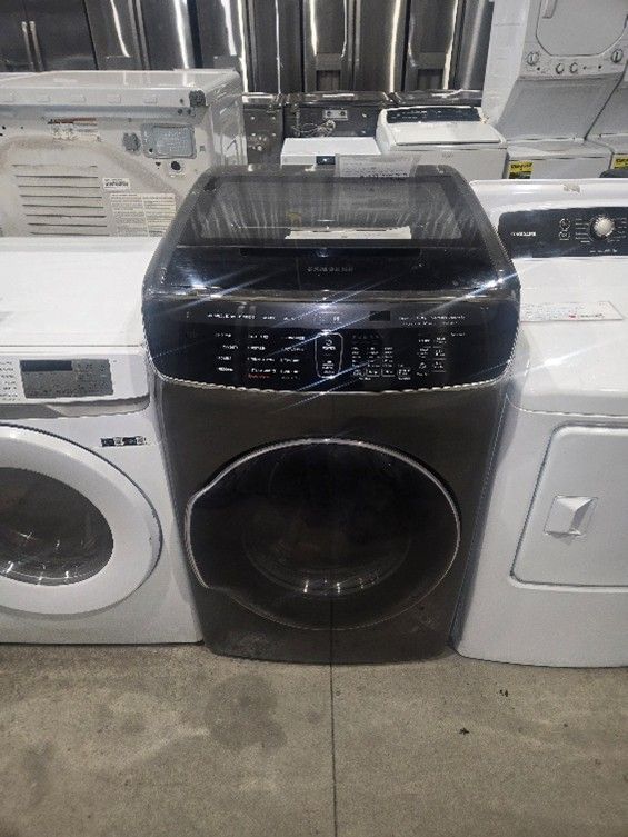 Black washing machine between two white appliances.