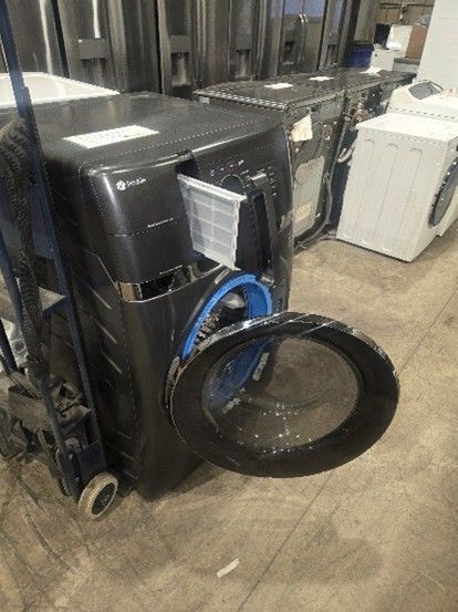 Black washing machine with open door, lint filter visible, sitting on a dolly in a warehouse.