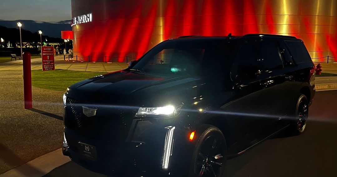 A black suv is parked in front of a building with red lights.
