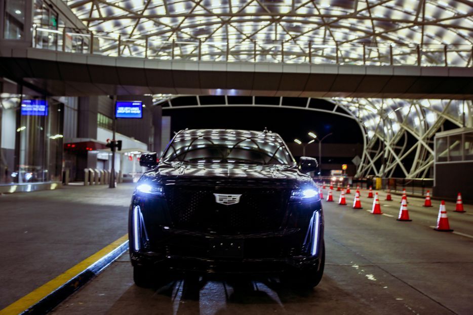 A black cadillac is parked in a parking lot at night.