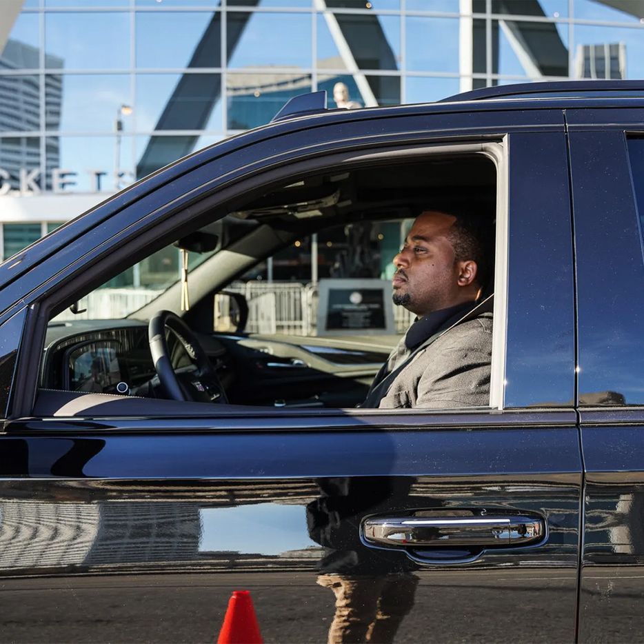 A man is sitting in a car with the letter a in the background