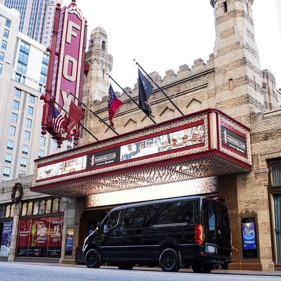 A black van is parked in front of a large building.