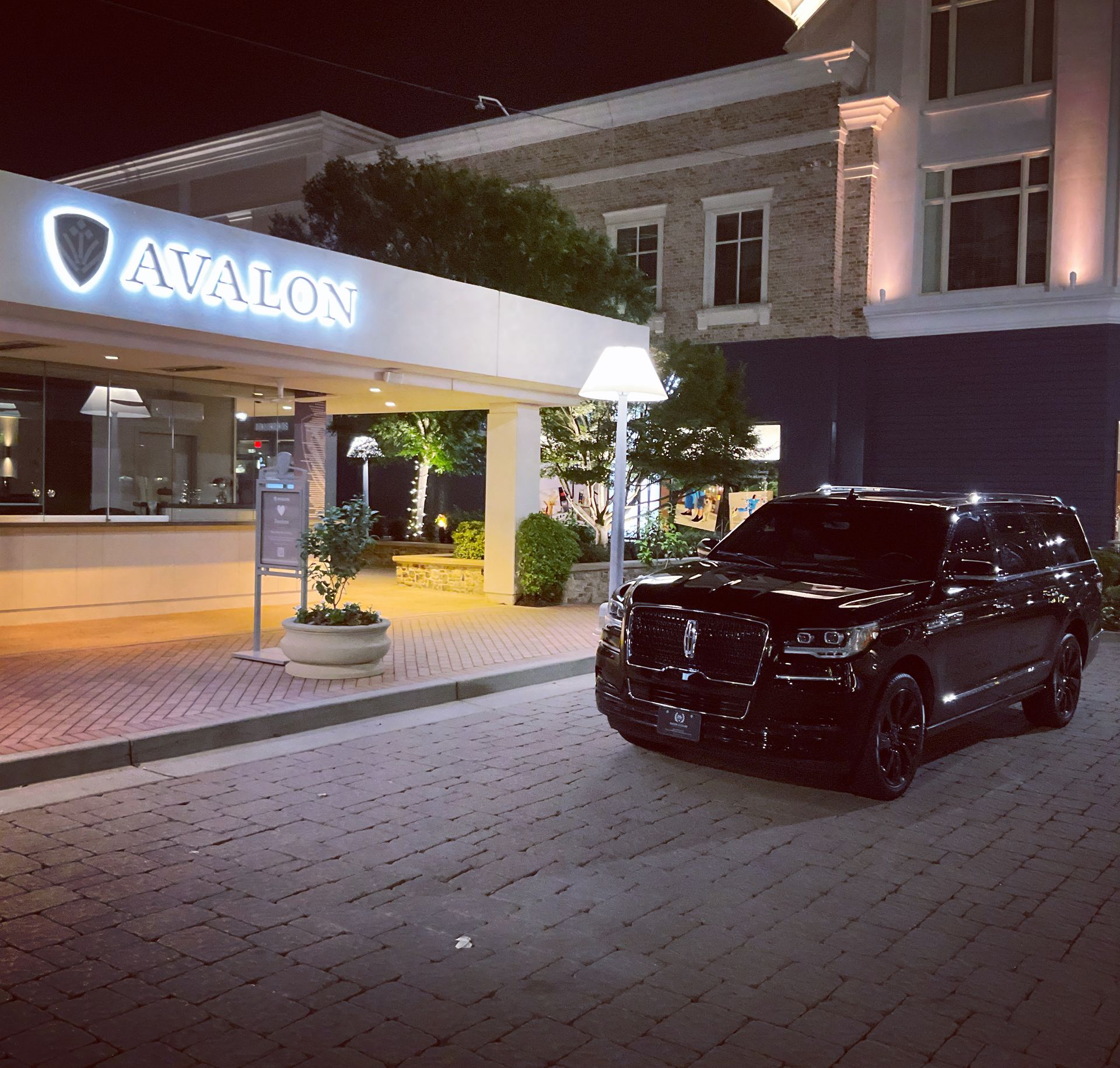 A black suv is parked in front of a building that says avalon