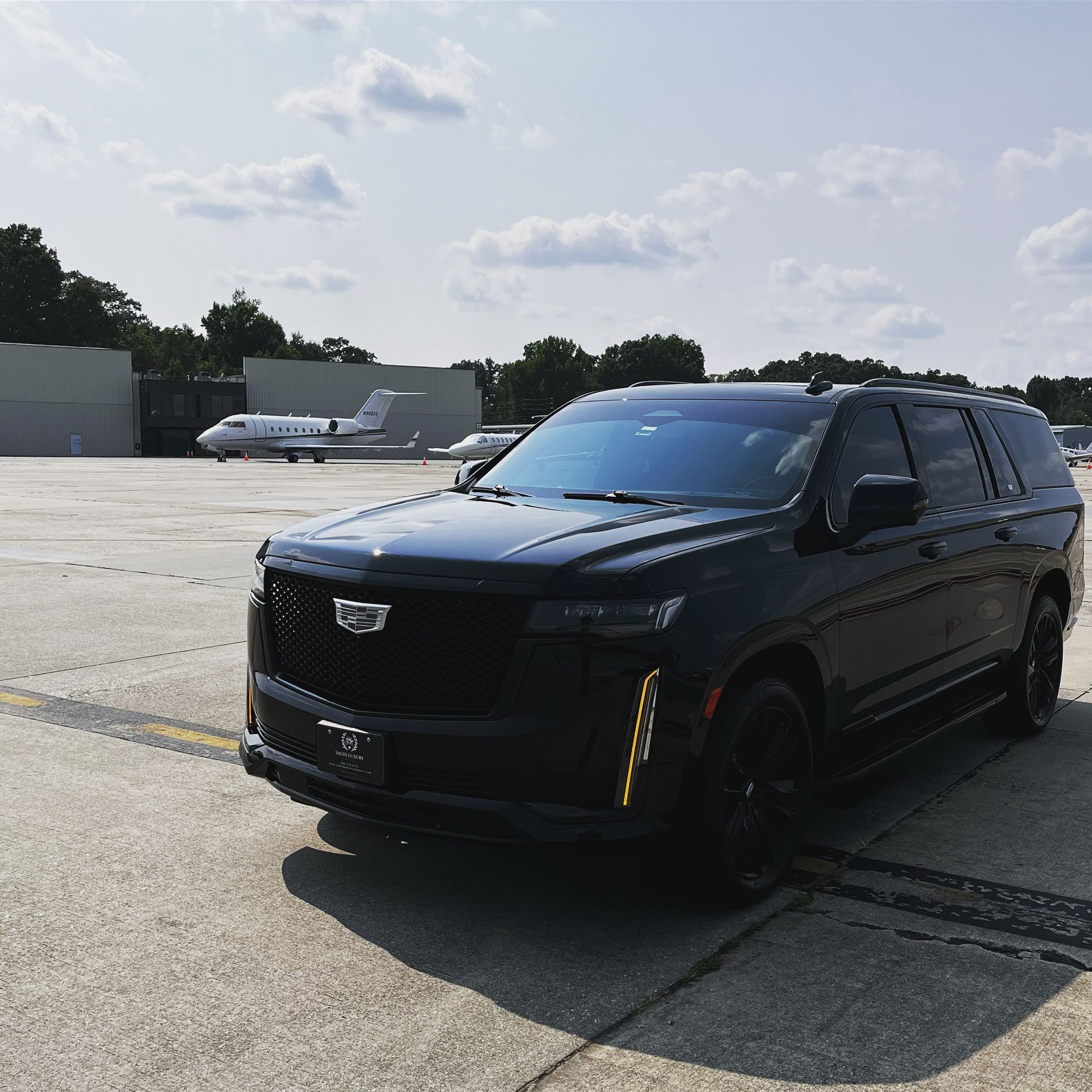 A black suv is parked on a runway with a plane in the background