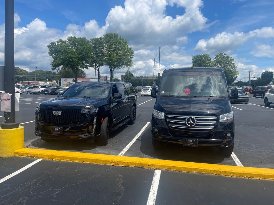 Two black cars are parked next to each other in a parking lot.