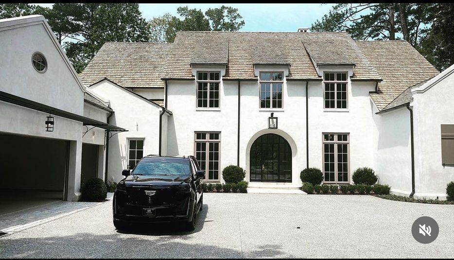 A black car is parked in front of a large white house