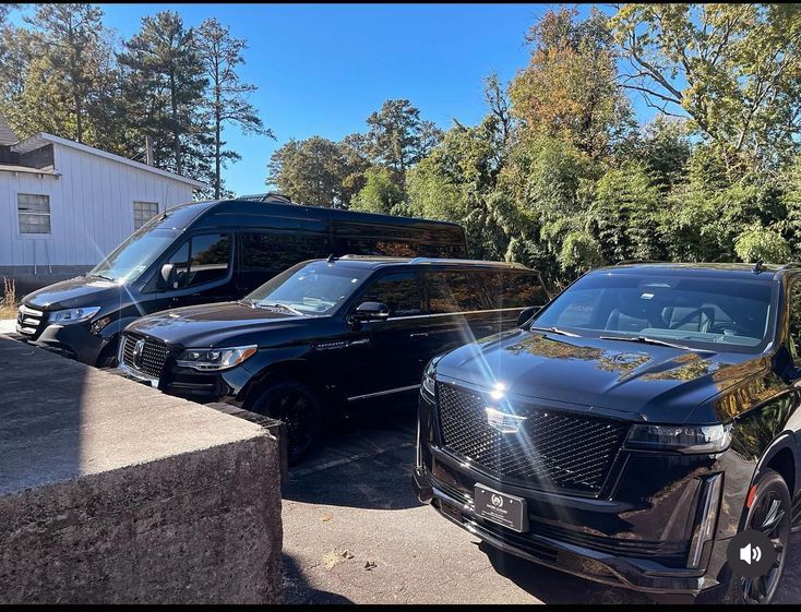 Three black cars are parked next to each other in a parking lot.