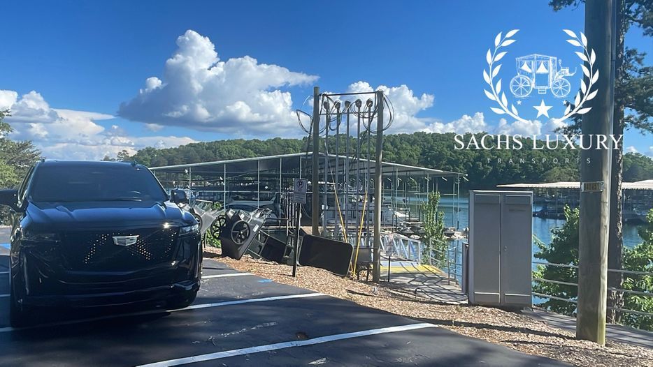 A black car is parked on the side of a road next to a body of water.