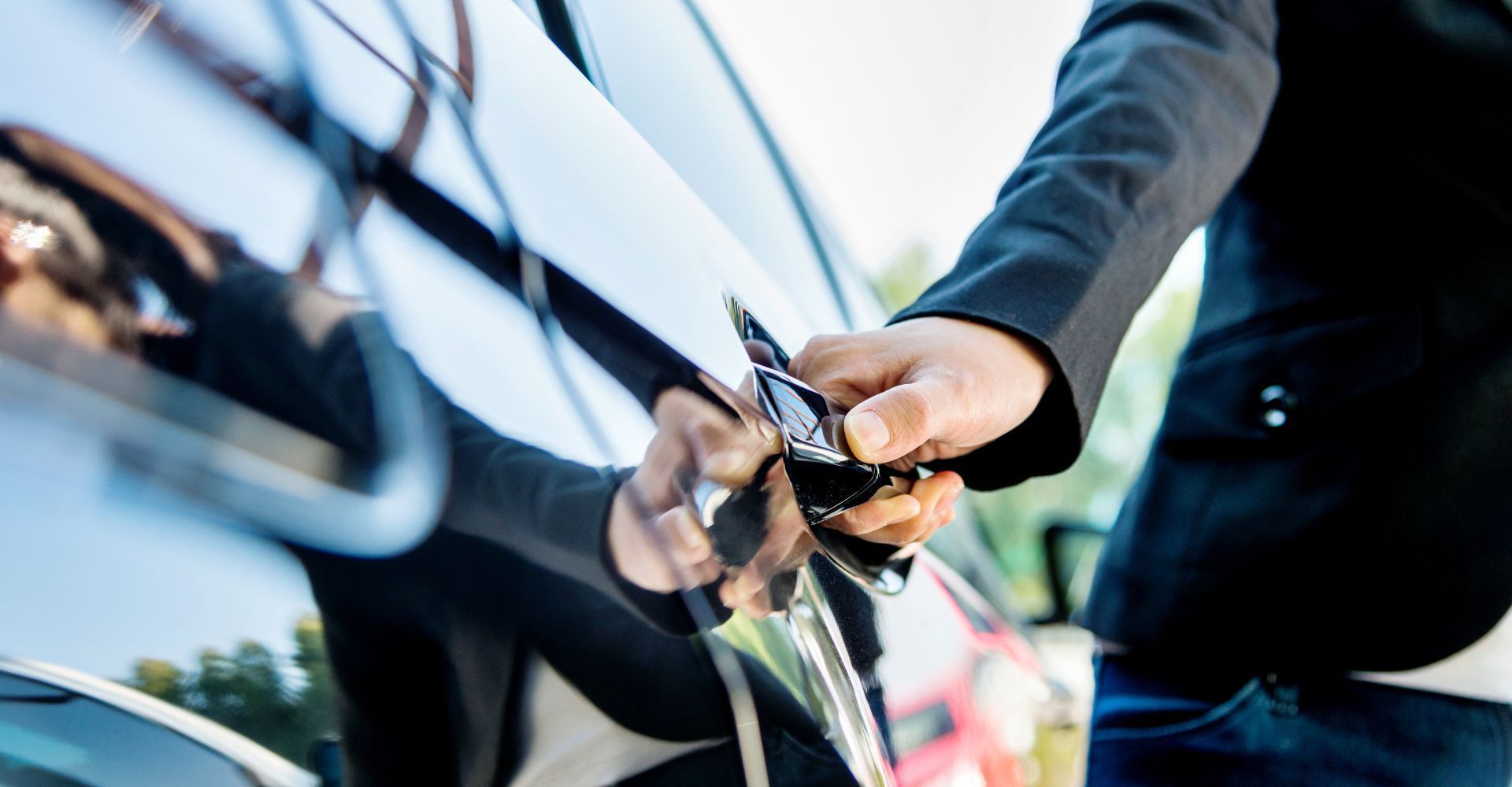 A man is holding a car key in front of a car.