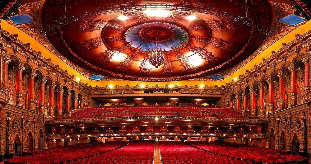 A large auditorium with red seats and a circular ceiling