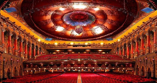 A large auditorium with red seats and a circular ceiling