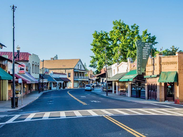 Street scene of quaint shops and businesses with awnings under a bright blue sky.