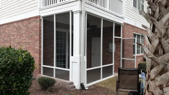 Garage with open screen door. Brick facade, blue siding, gray sky.