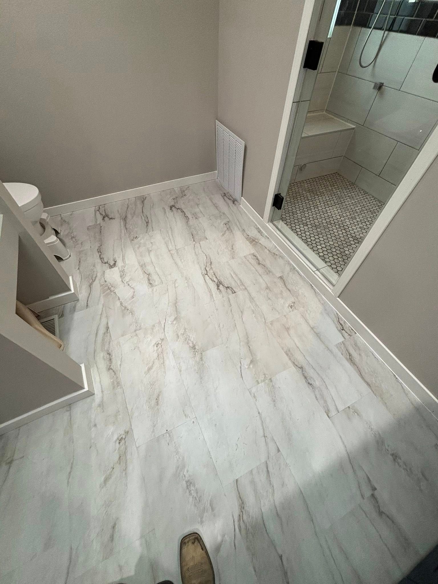 Bathroom with marble-look flooring, a glass shower, and neutral walls.