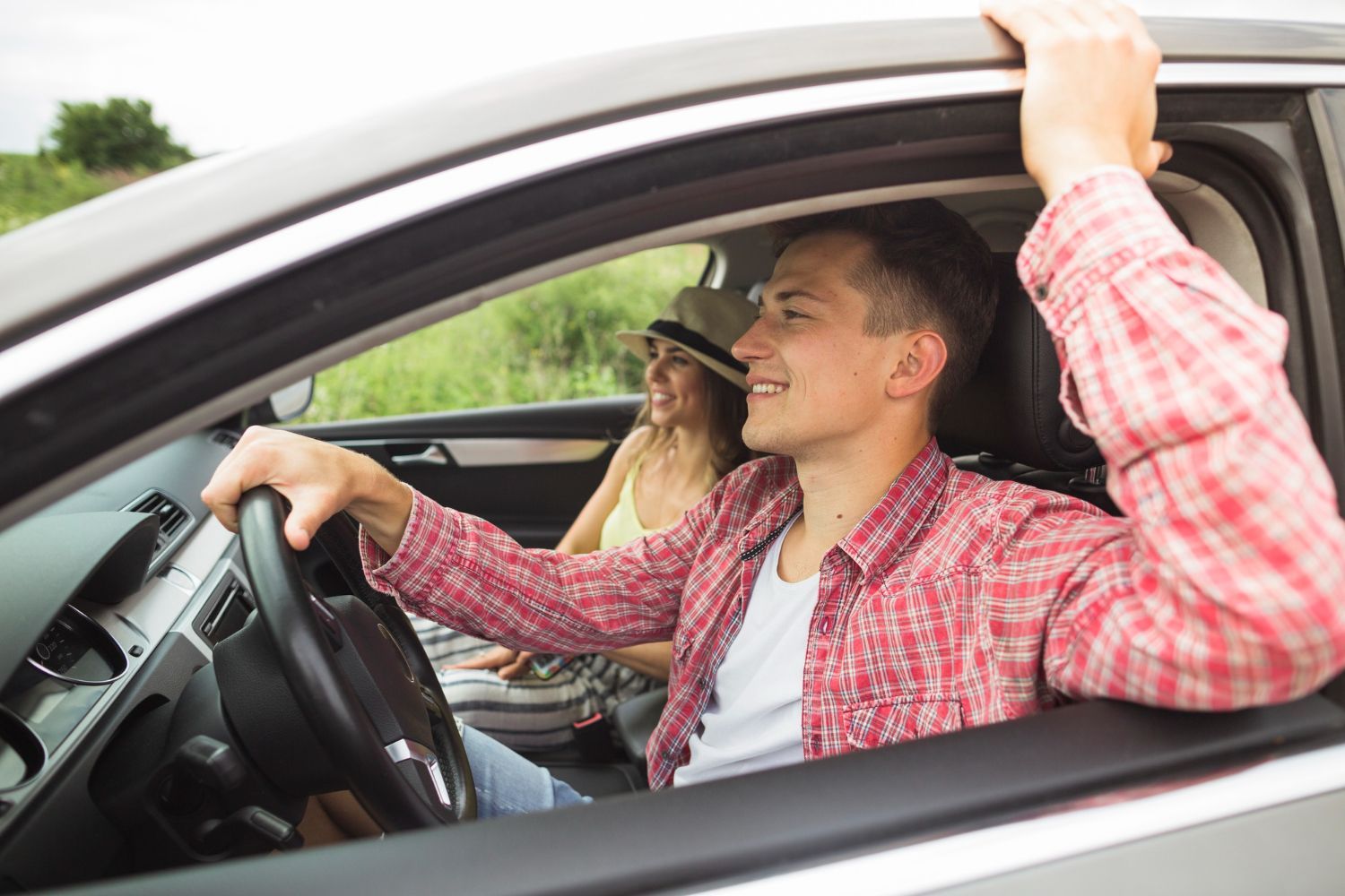 A man is driving a car with a woman sitting in the back seat.