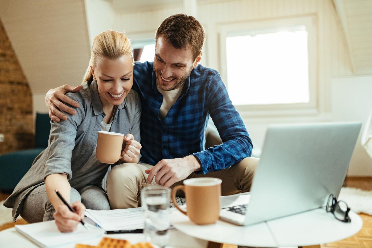 A man and a woman are sitting on a couch looking at a laptop.