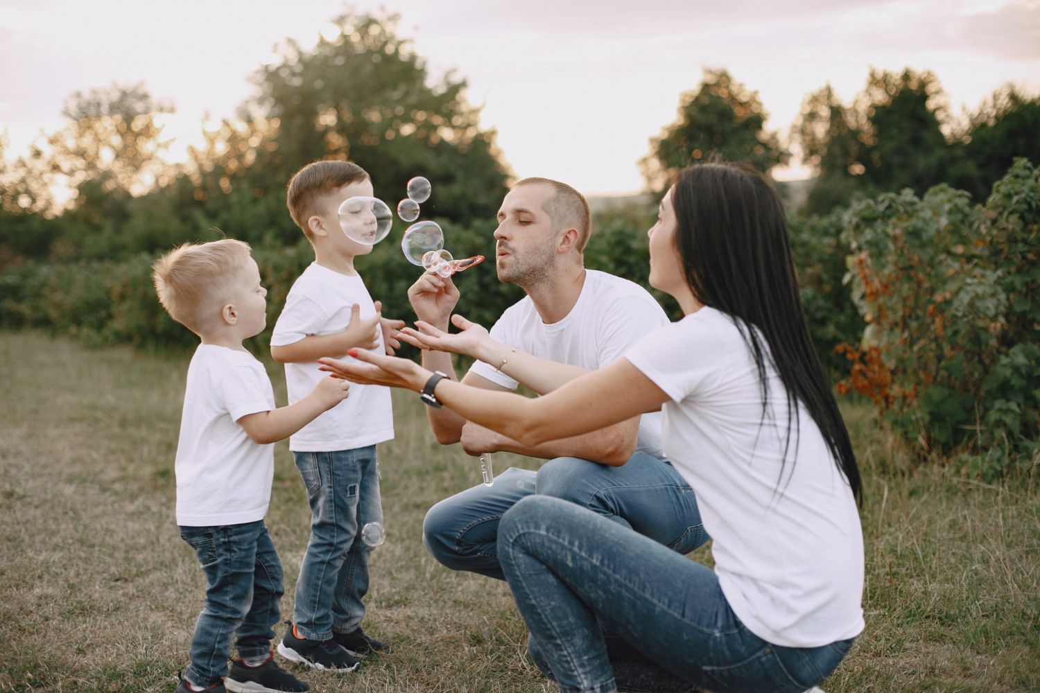 A family is blowing soap bubbles in a park.