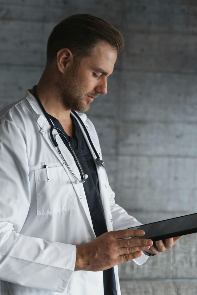 A doctor with a stethoscope around his neck is using a tablet computer.