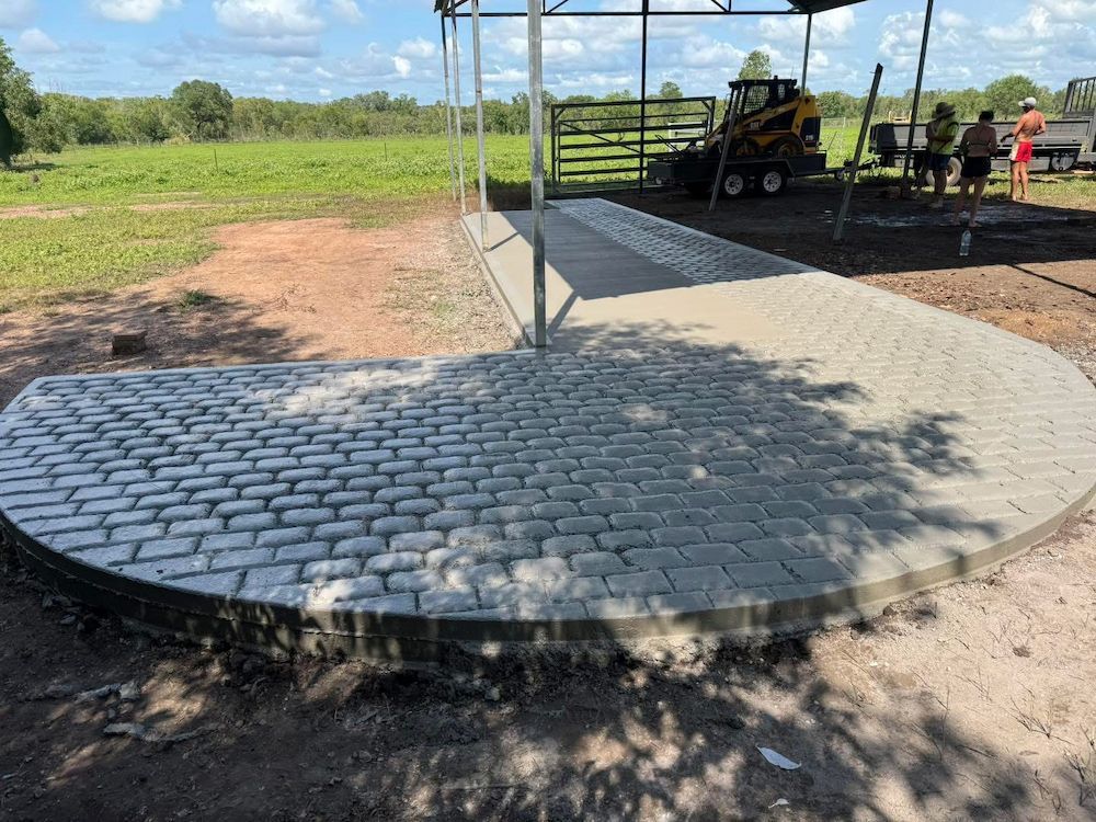 Curved Gray Brick Driveway Under a Shelter, Leading to a Pasture — Mobcon Construction in Palmerston, NT