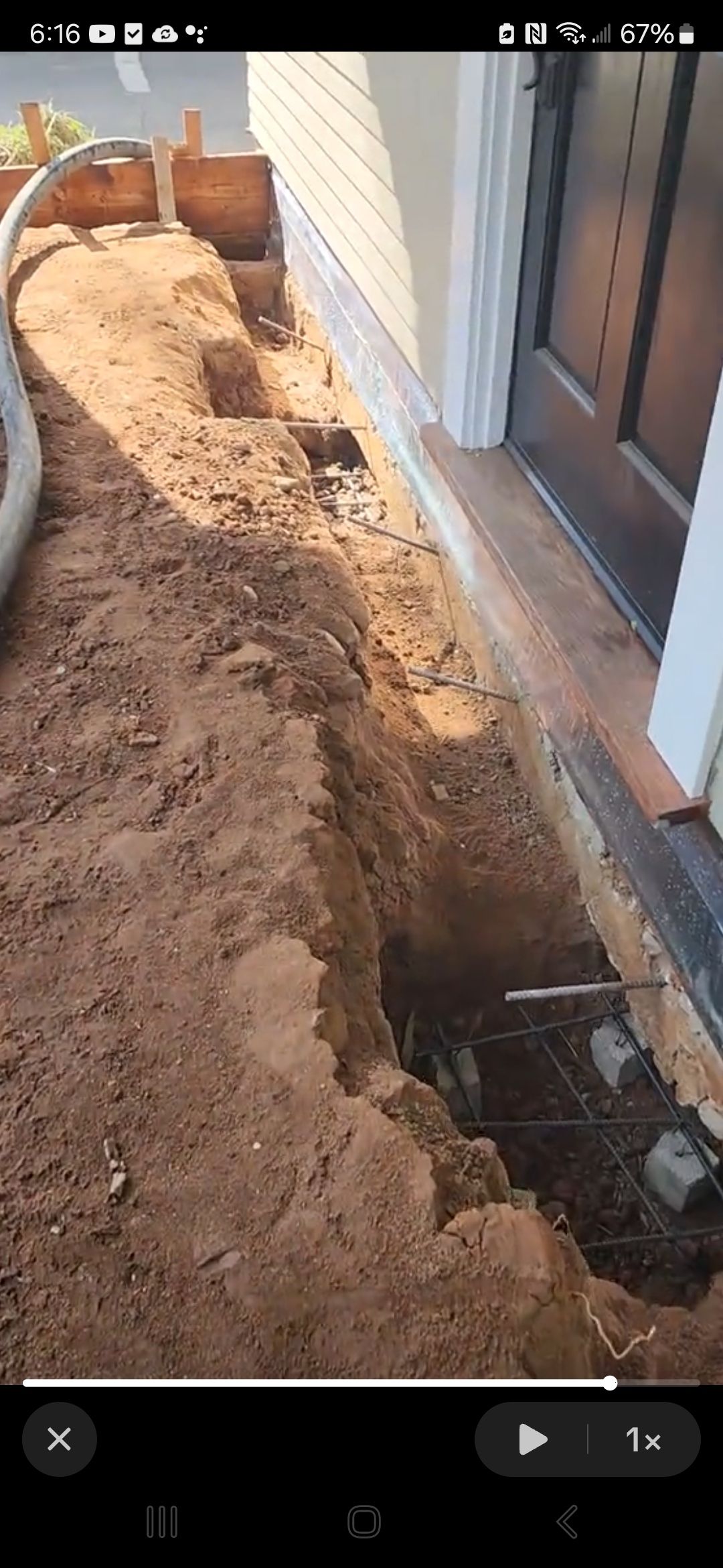 A person is digging a hole in the ground in front of a house.