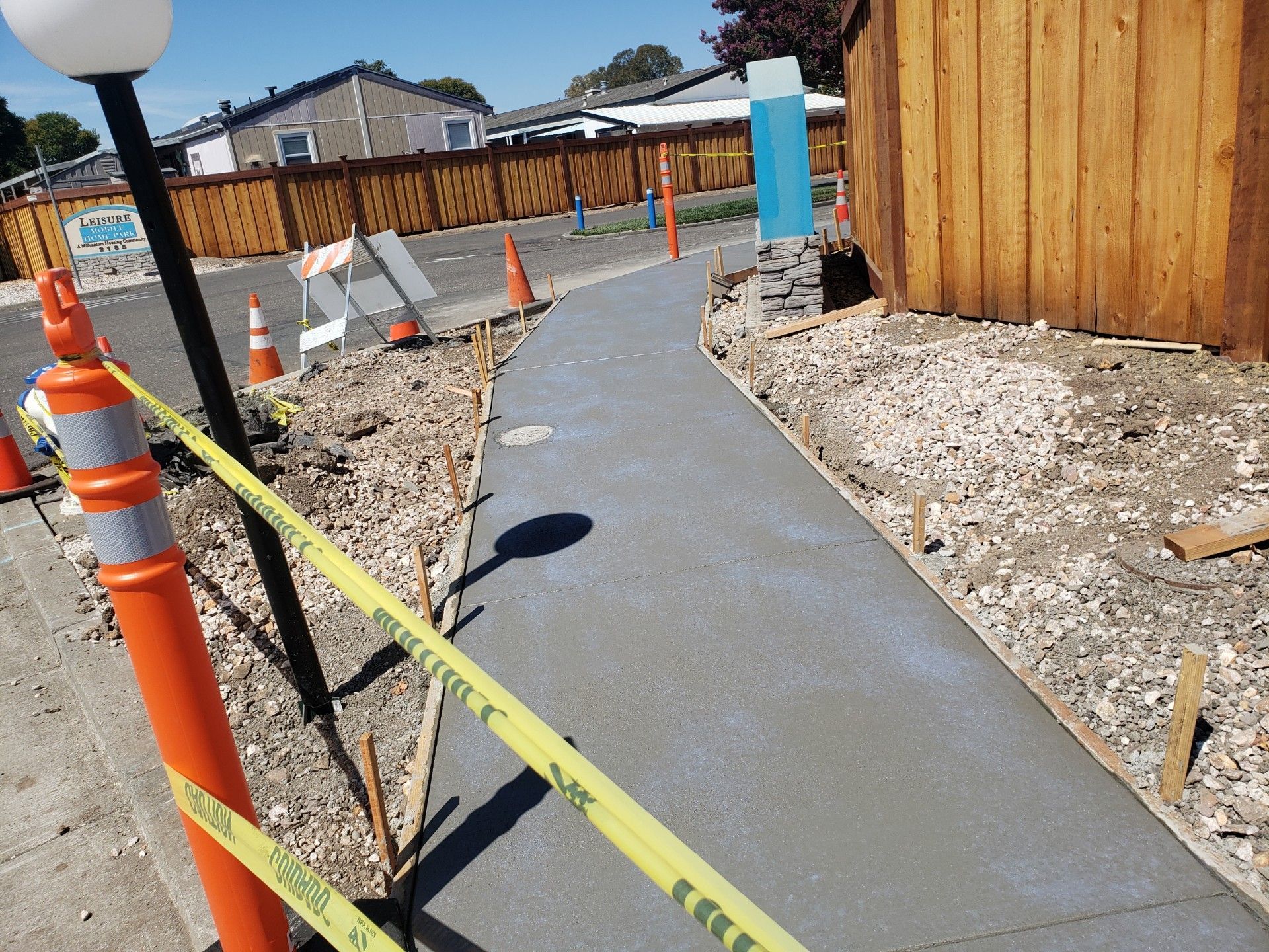 A concrete walkway is being built next to a wooden fence