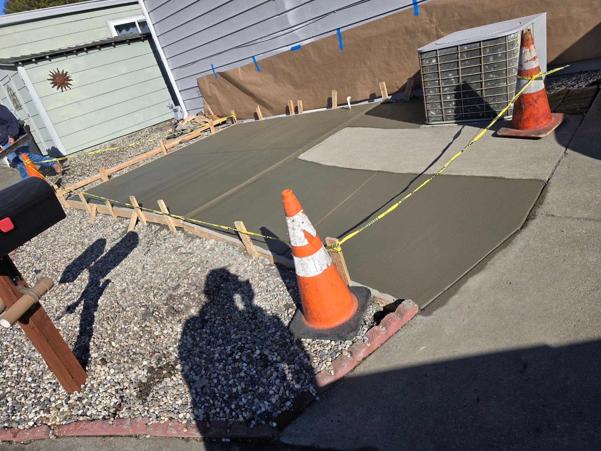 A concrete driveway leading to a backyard filled with potted plants.