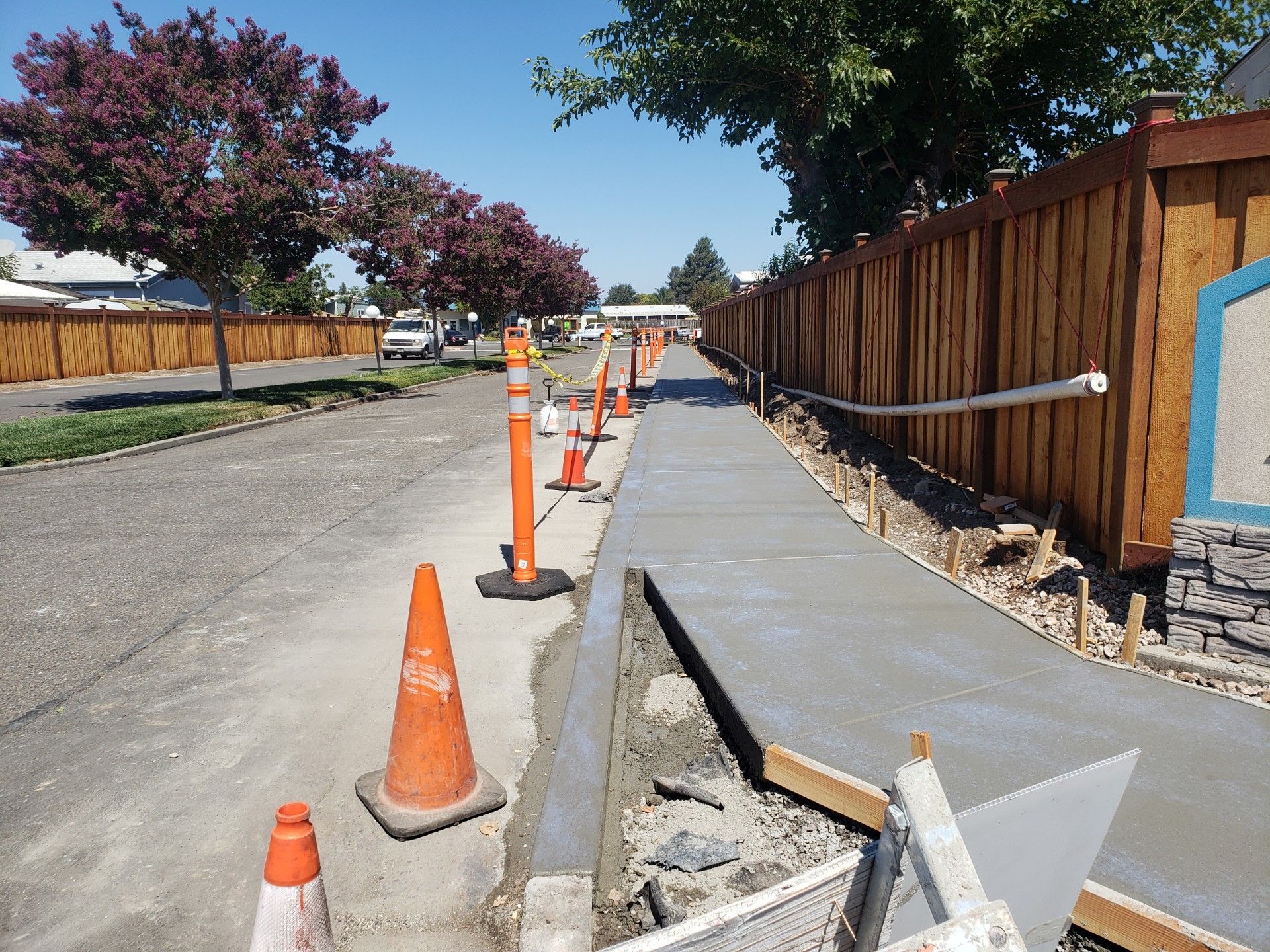 A sidewalk is being built next to a wooden fence