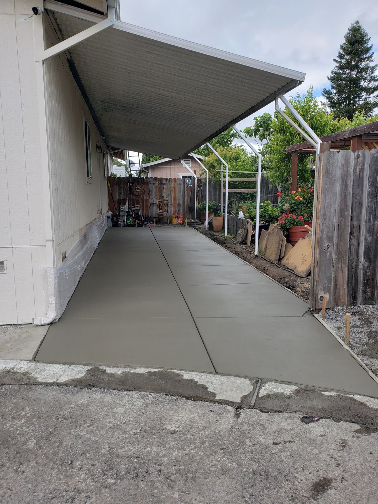 A concrete driveway with a canopy over it next to a house.