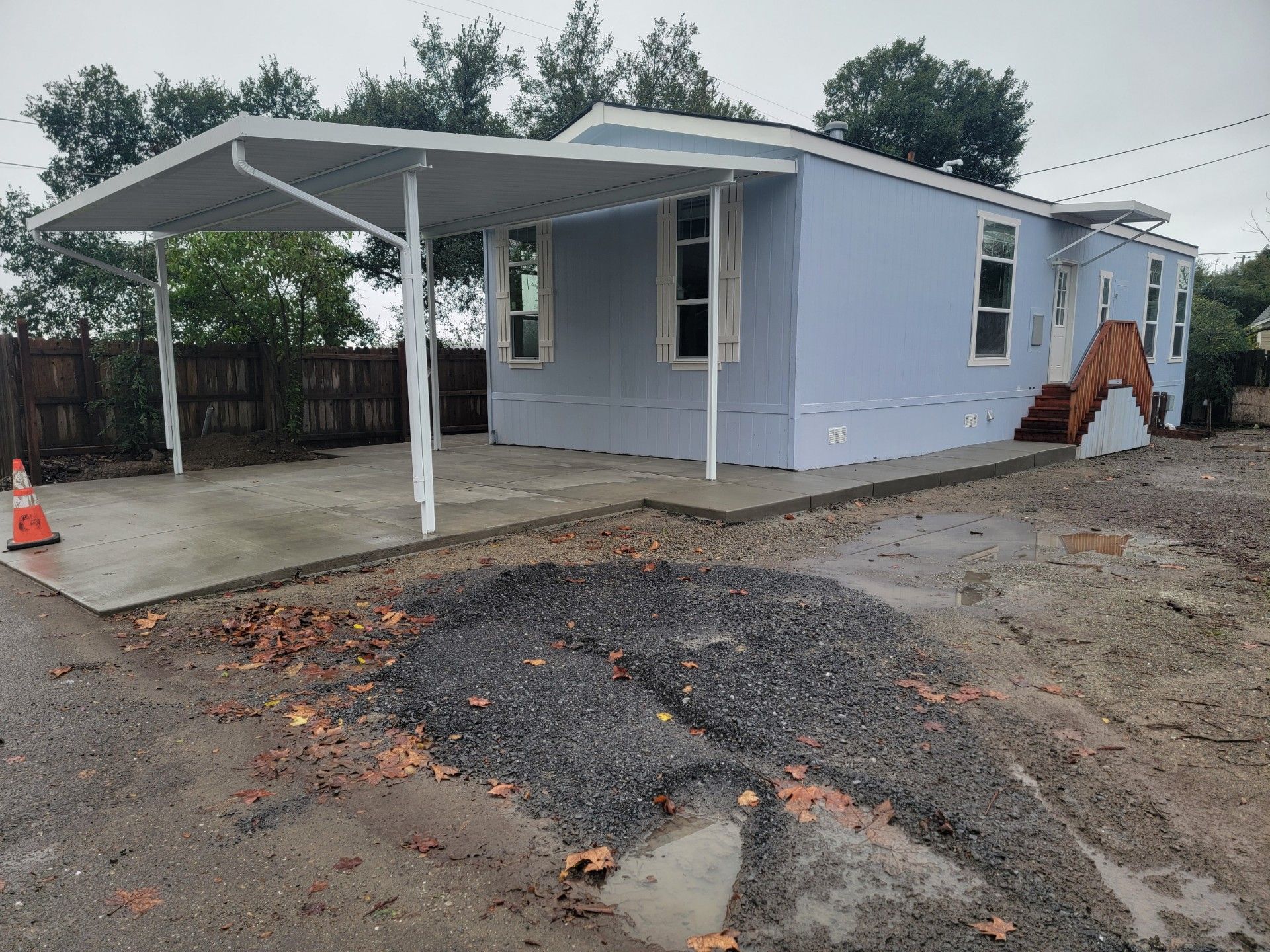 A blue mobile home with a carport in front of it.