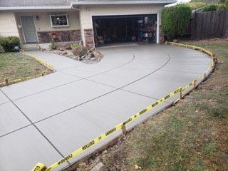 A concrete walkway leading to a house with a tree in the background.