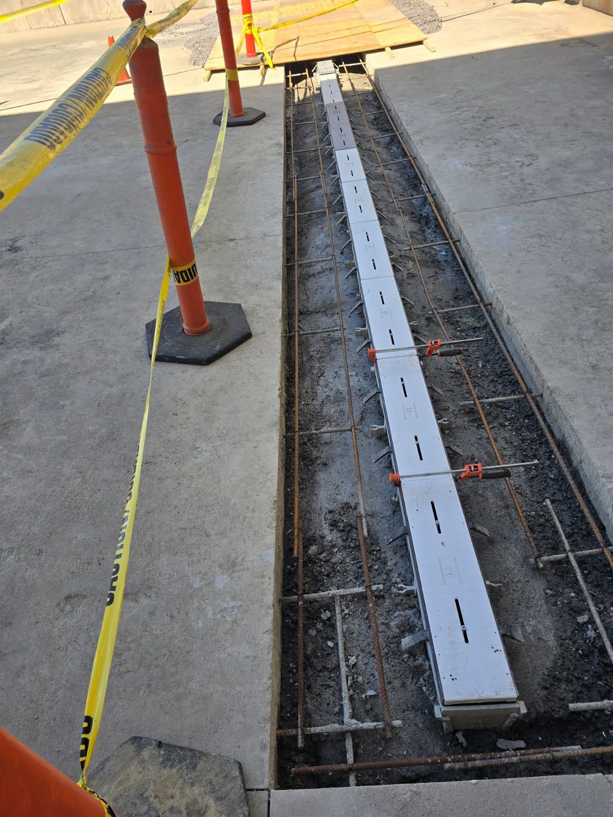 A long piece of concrete is being poured into a hole in the ground.