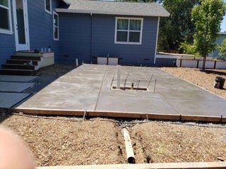 A concrete patio is being built in front of a blue house.