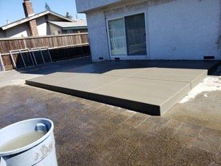 A cup of coffee is sitting next to a concrete patio.