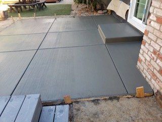 A concrete patio is being built in front of a brick house.
